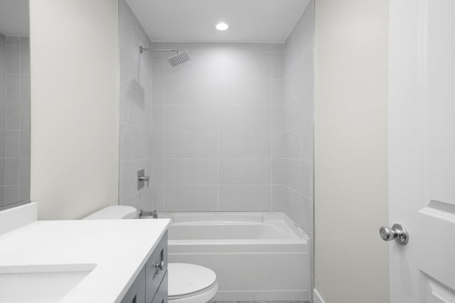 full bathroom featuring vanity, tiled shower / bath combo, and toilet