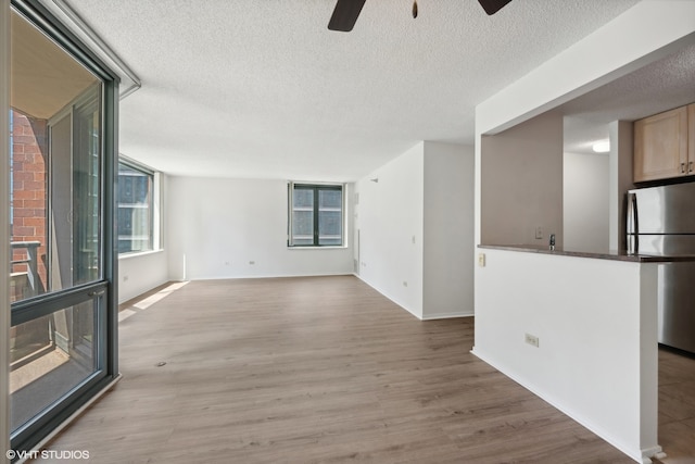 interior space with light wood-type flooring, a textured ceiling, and ceiling fan