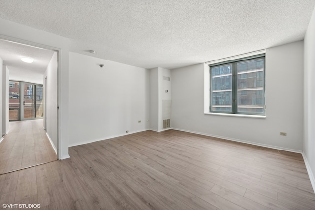 unfurnished room featuring a textured ceiling and light hardwood / wood-style flooring