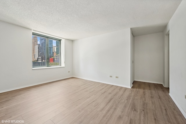 empty room with a textured ceiling and light hardwood / wood-style floors