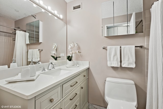 bathroom with a textured ceiling, curtained shower, vanity, and toilet