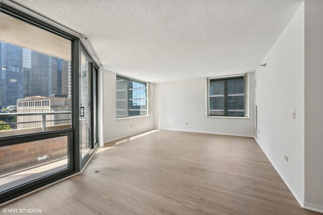 spare room featuring a textured ceiling, light hardwood / wood-style floors, and a wall of windows