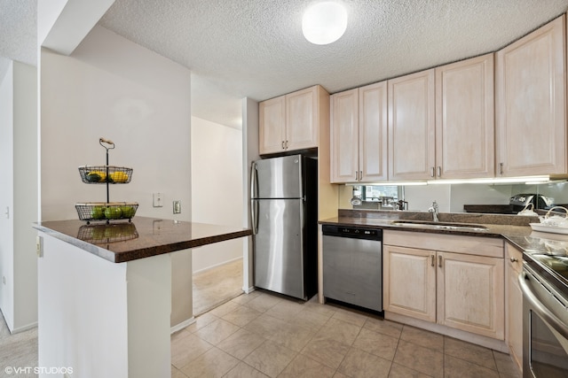 kitchen with light tile patterned flooring, kitchen peninsula, stainless steel appliances, a textured ceiling, and sink