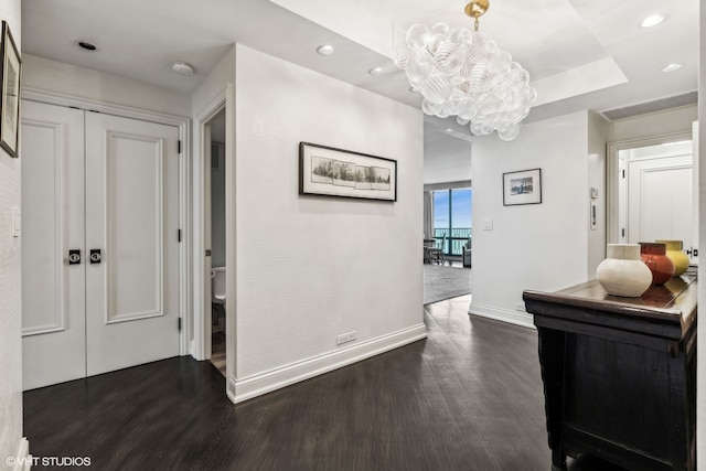 hall with a notable chandelier and dark hardwood / wood-style floors