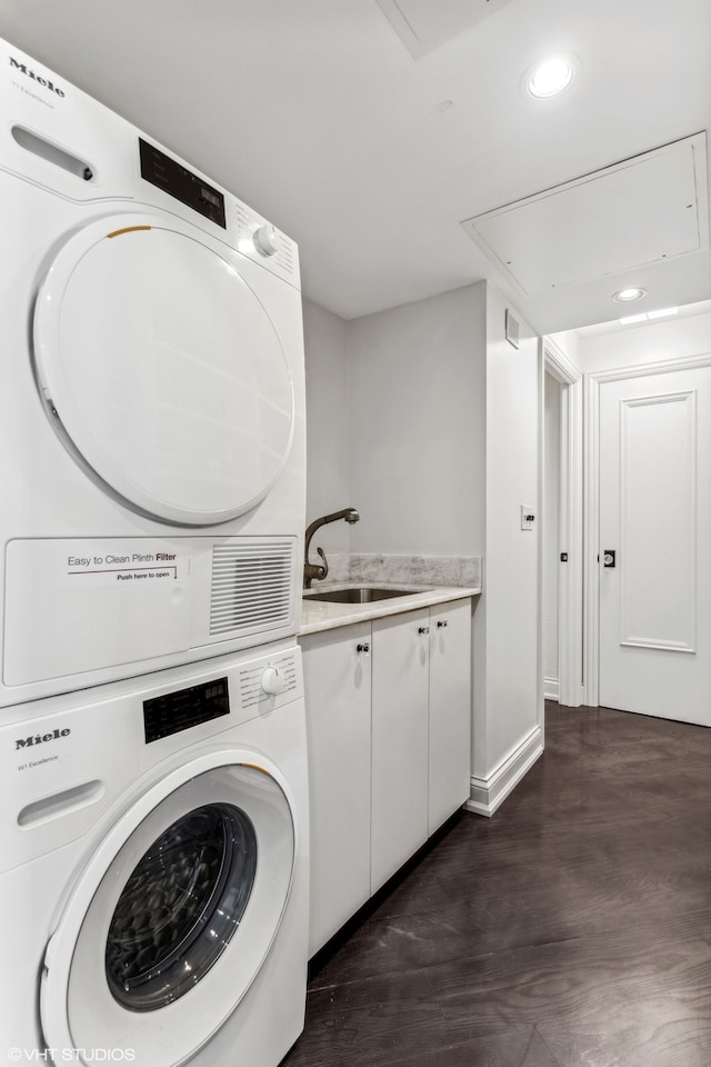 washroom with dark hardwood / wood-style flooring, cabinets, sink, and stacked washer and dryer