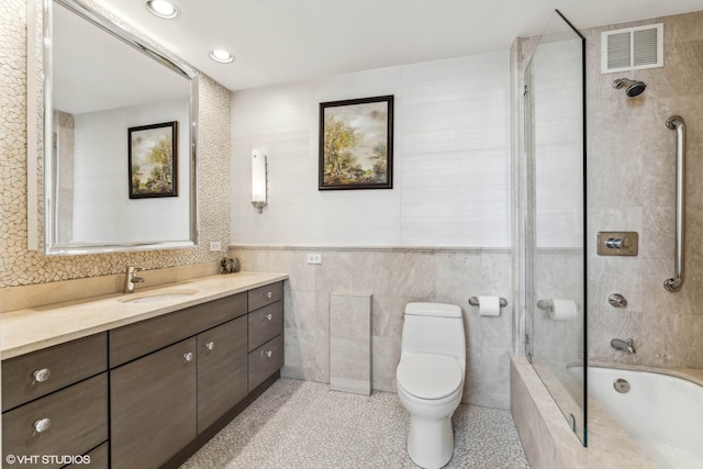 full bathroom with vanity, tiled shower / bath, toilet, and tile walls