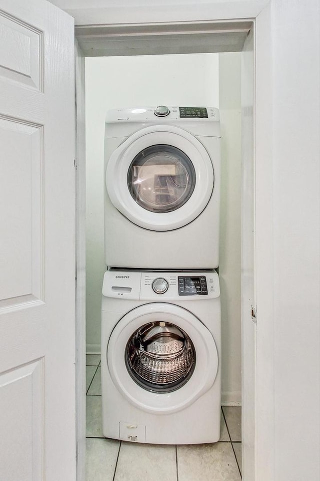 laundry room featuring light tile patterned floors and stacked washer and clothes dryer