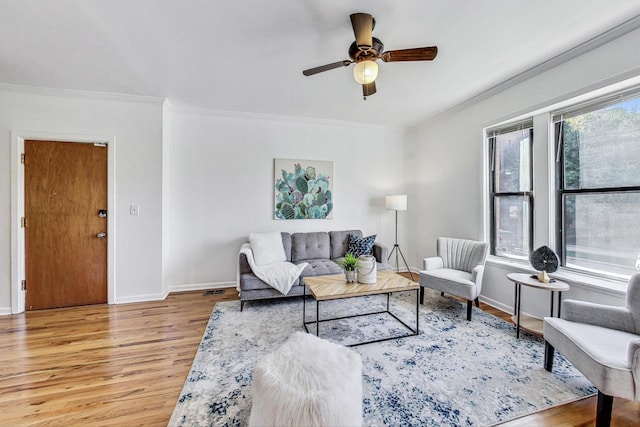 living room featuring ceiling fan, ornamental molding, and light wood-type flooring