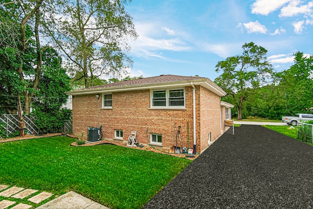 rear view of property featuring central AC and a lawn