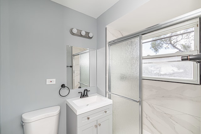 bathroom featuring vanity, toilet, and a shower with shower door