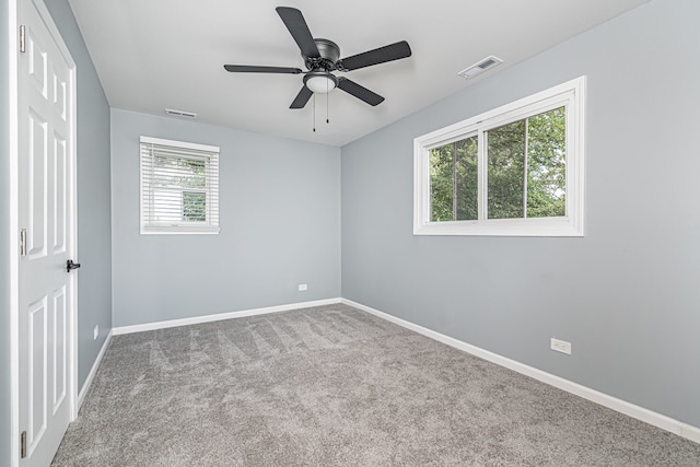 carpeted spare room featuring ceiling fan and a wealth of natural light