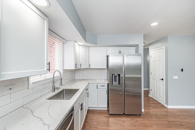 kitchen featuring light hardwood / wood-style flooring, backsplash, sink, white cabinetry, and appliances with stainless steel finishes