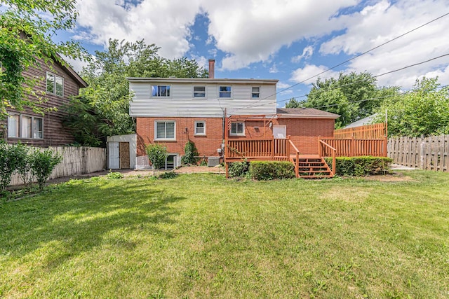 rear view of house featuring a wooden deck, a yard, and a shed