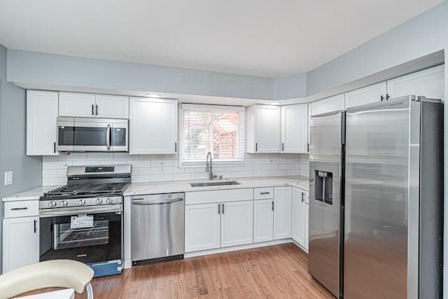 kitchen featuring appliances with stainless steel finishes, white cabinetry, and sink