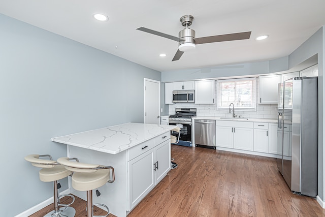 kitchen featuring sink, dark hardwood / wood-style flooring, stainless steel appliances, white cabinets, and light stone counters