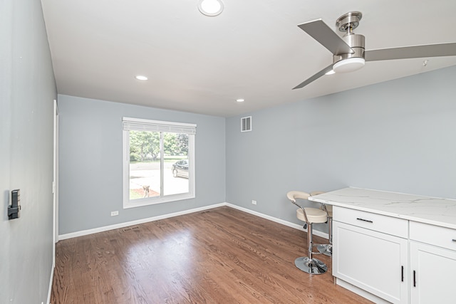 unfurnished office with ceiling fan and dark hardwood / wood-style floors