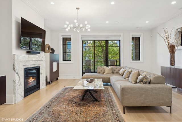 living room with a notable chandelier, light hardwood / wood-style floors, ornamental molding, and a fireplace