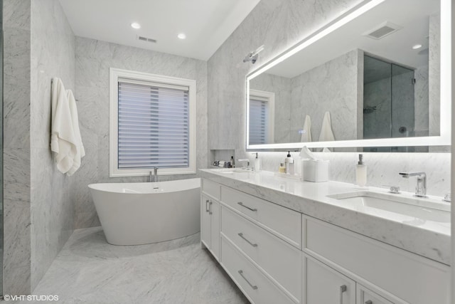 bathroom with tile walls, separate shower and tub, and vanity