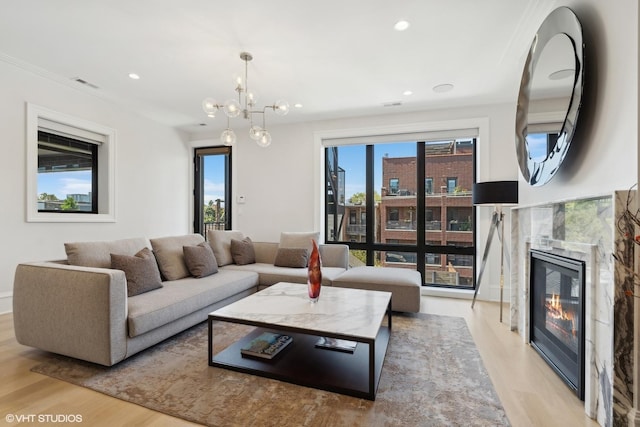 living room featuring a notable chandelier, a premium fireplace, and light hardwood / wood-style floors