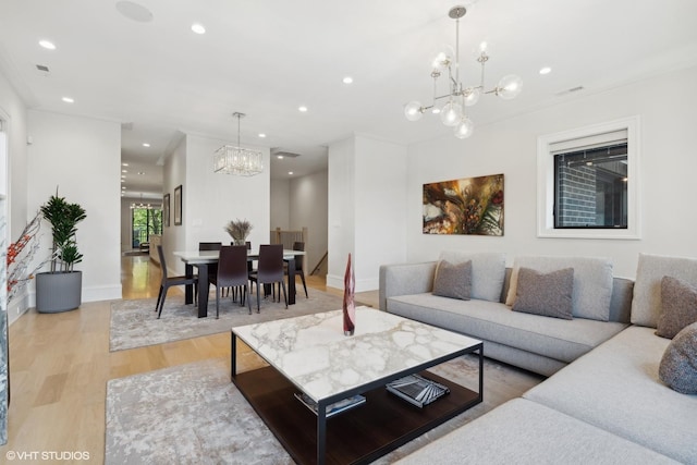 living room featuring ornamental molding, light wood-type flooring, and a chandelier