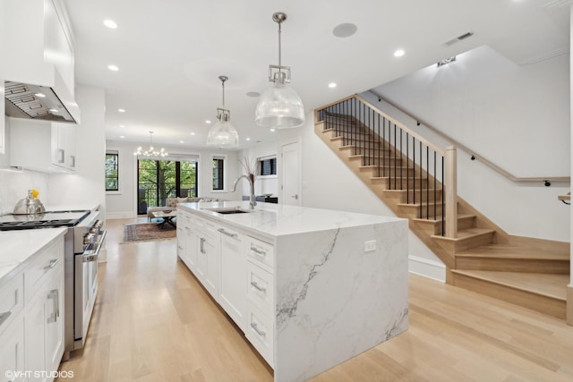 kitchen with hanging light fixtures, a large island with sink, stainless steel stove, sink, and custom exhaust hood