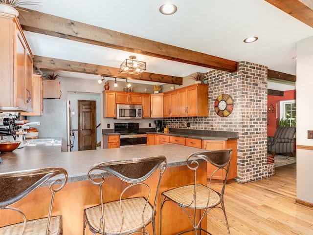 kitchen featuring a breakfast bar area, stainless steel appliances, light wood-type flooring, and kitchen peninsula