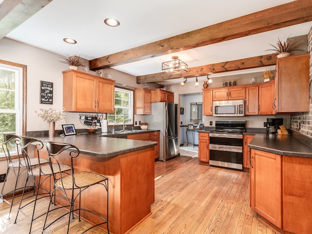 kitchen with a breakfast bar, light hardwood / wood-style floors, sink, kitchen peninsula, and stainless steel appliances