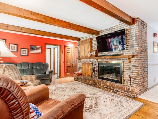 living room with light wood-type flooring, beamed ceiling, and a fireplace