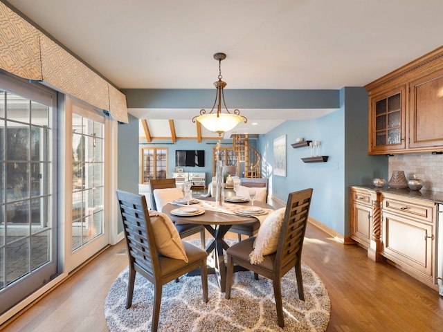 dining space with light hardwood / wood-style floors and beamed ceiling