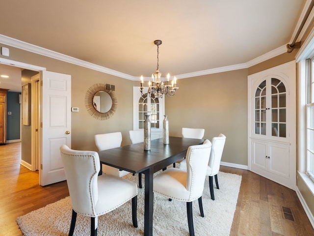 dining space featuring a notable chandelier, light hardwood / wood-style flooring, and ornamental molding