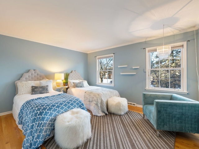 bedroom featuring hardwood / wood-style floors, multiple windows, and ornamental molding