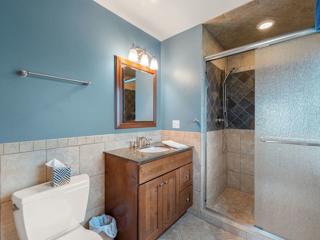 bathroom with toilet, walk in shower, vanity, and tile walls