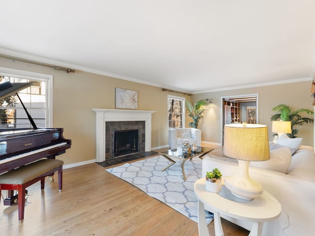 living room featuring a tiled fireplace, crown molding, and light hardwood / wood-style flooring