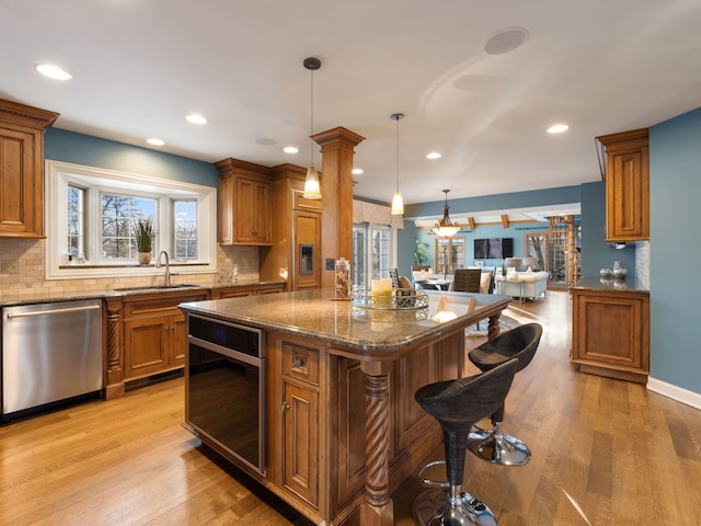 kitchen with dishwasher, hanging light fixtures, a center island, dark stone countertops, and sink