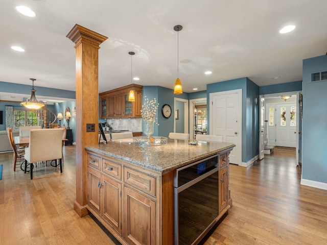 kitchen with wine cooler, light hardwood / wood-style flooring, pendant lighting, and ornate columns