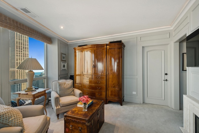 sitting room featuring a high end fireplace, light colored carpet, and crown molding