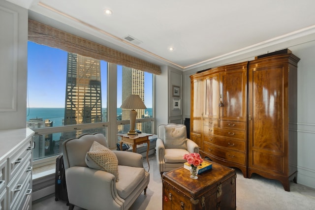 living area with crown molding, a water view, and light carpet