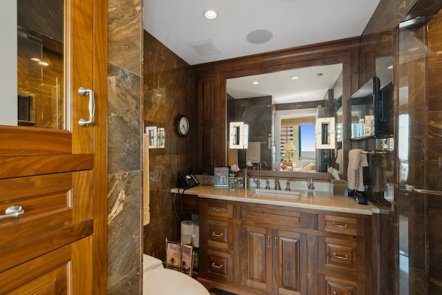 bathroom with tile walls, vanity, and toilet