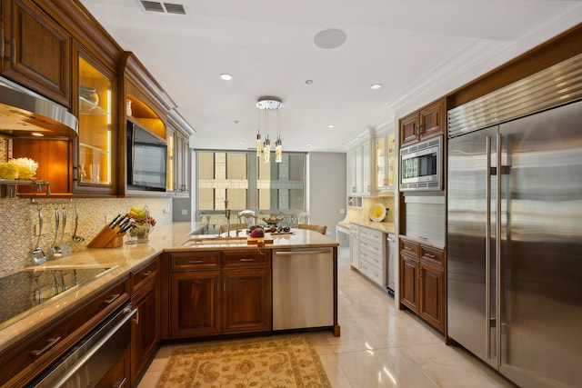 kitchen featuring pendant lighting, kitchen peninsula, tasteful backsplash, built in appliances, and an inviting chandelier