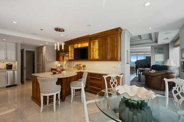 kitchen with pendant lighting, kitchen peninsula, a tray ceiling, a kitchen bar, and decorative backsplash