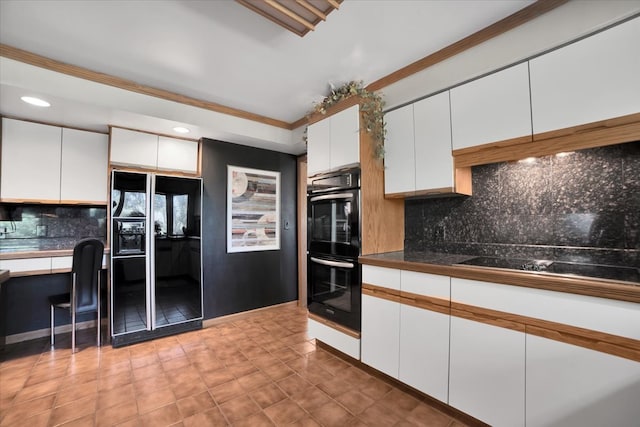 kitchen featuring white cabinets, backsplash, ornamental molding, and black appliances