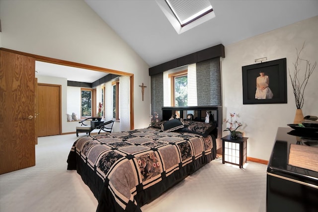 carpeted bedroom featuring a skylight and high vaulted ceiling