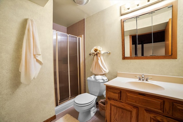 bathroom featuring tile patterned flooring, a shower with door, vanity, and toilet