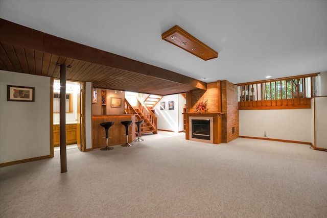 unfurnished living room with light colored carpet, beamed ceiling, and a fireplace