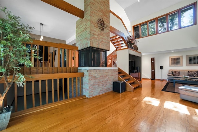 living room with wood-type flooring, beamed ceiling, and high vaulted ceiling