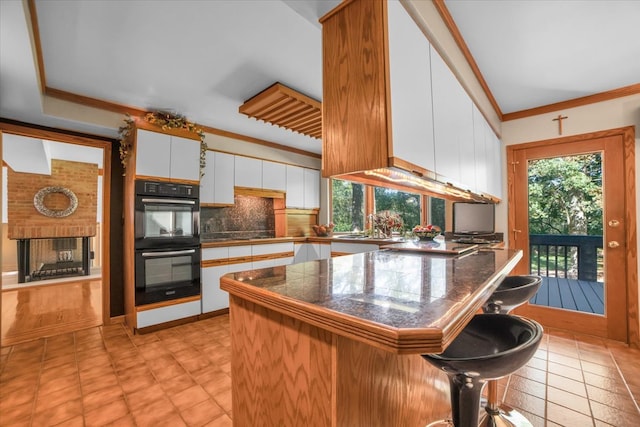 kitchen with a kitchen breakfast bar, decorative backsplash, white cabinets, light tile patterned floors, and double oven