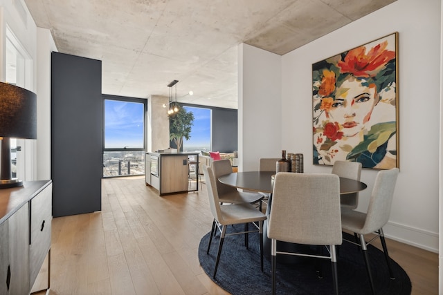 dining area with a wall of windows and light wood-type flooring