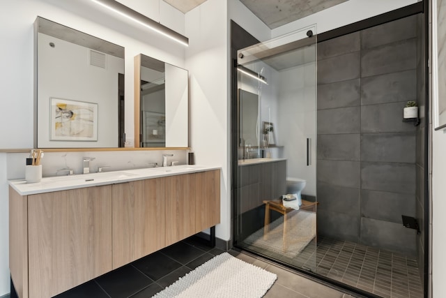 bathroom with tile patterned floors, a shower with door, vanity, and toilet