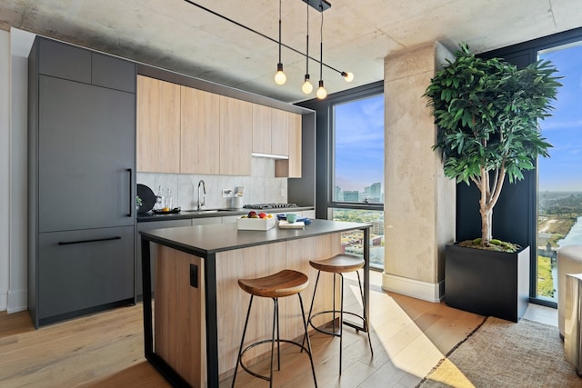 kitchen with sink, a kitchen island, light hardwood / wood-style floors, and decorative light fixtures