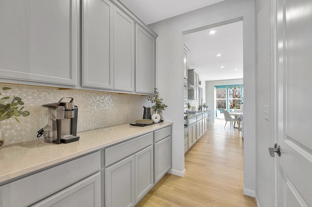 interior space with light stone countertops, backsplash, light hardwood / wood-style floors, and gray cabinetry